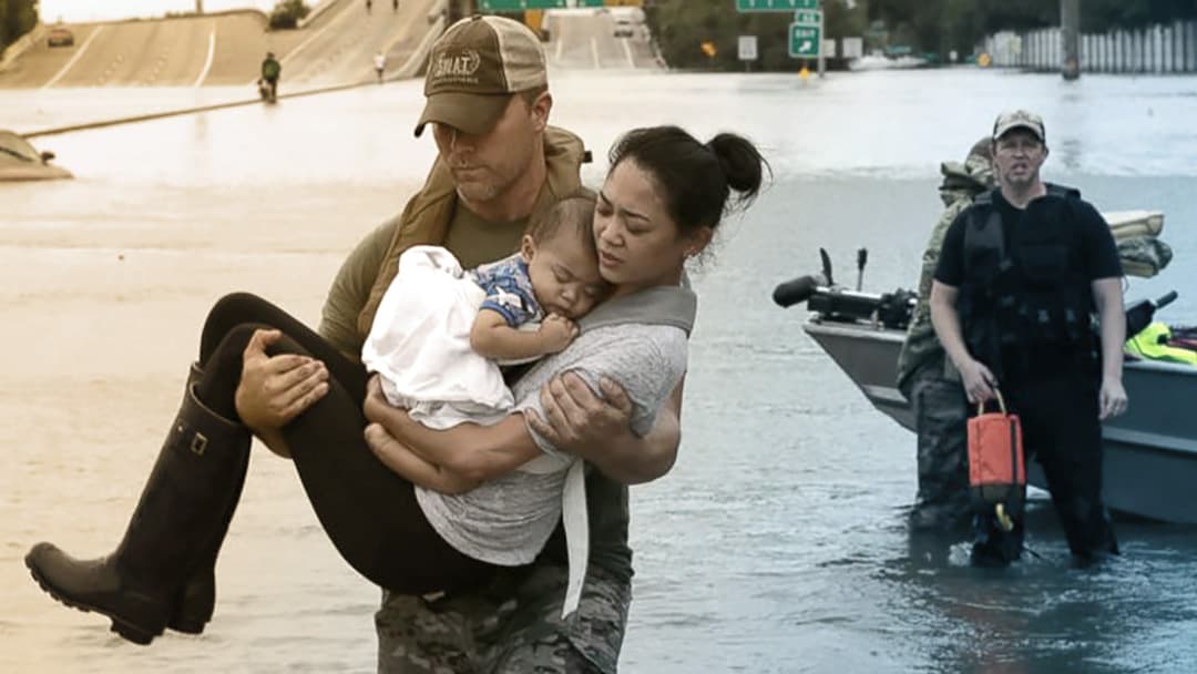 一名男子抱着一名妇女和她的孩子走过被洪水淹没的街道。