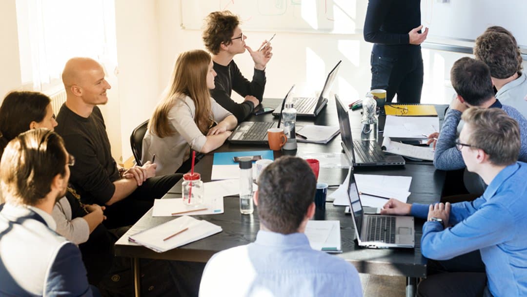 A man presents during a team meeting in a conference room