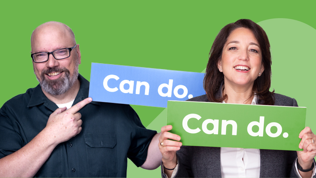 两名微笑的Smartsheet客户举着写有“can-do”的标语。